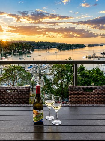 Sunset over Ganges Harbour and its marina, viewed from a Mariner's Loft balcony with wine glasses on the table